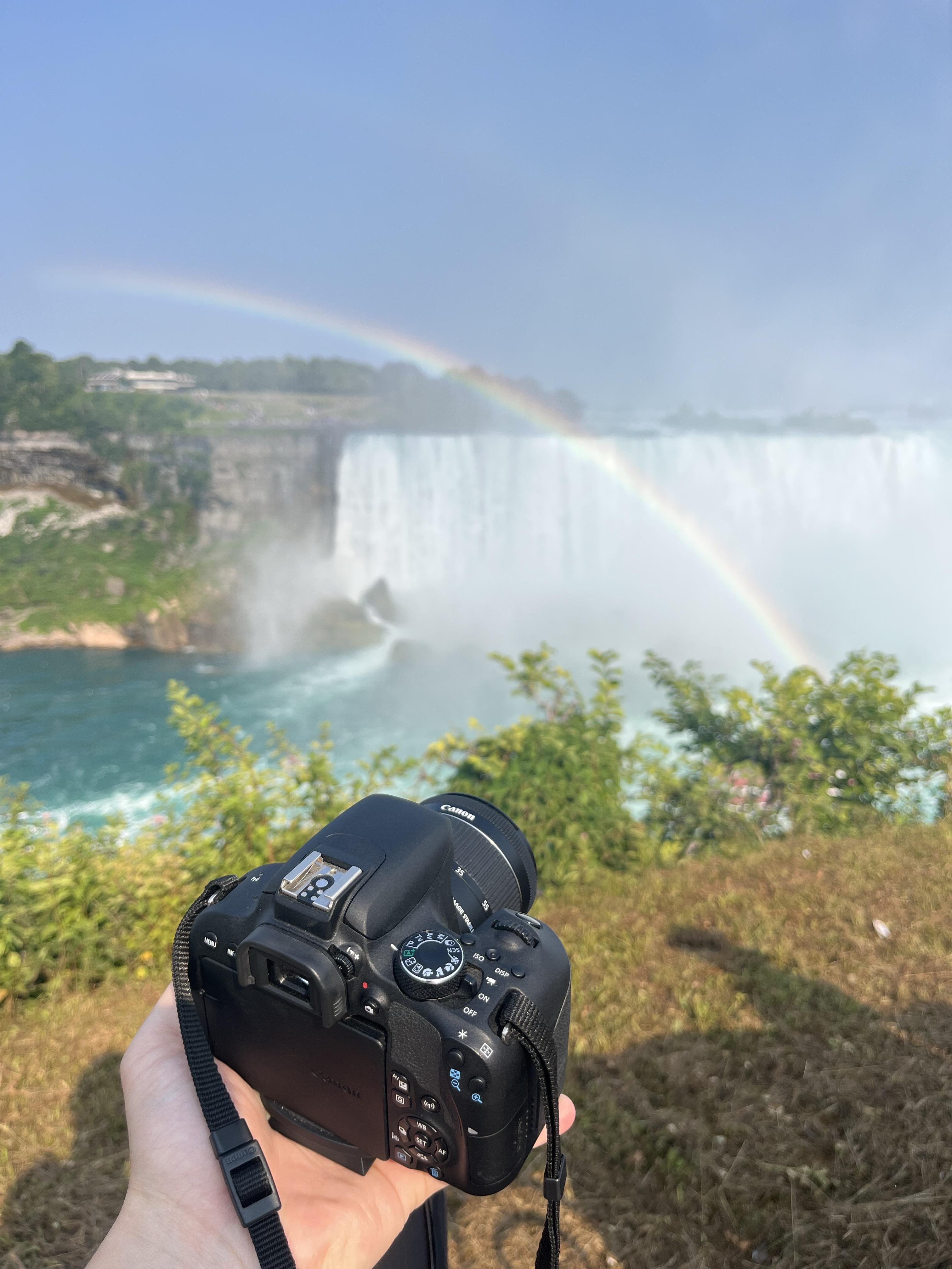 Camera held in hand in front of Niagara Falls